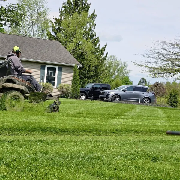 A Clean Fleet crew member mowing a residential lawn on a zero-turn mower